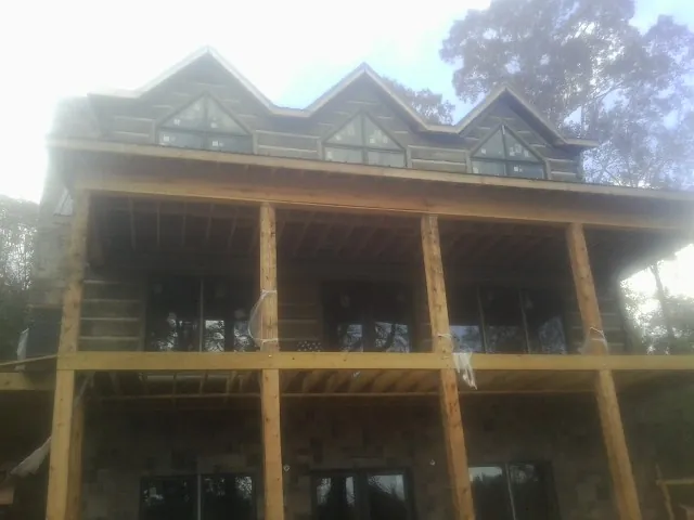 Dormers and porch framing on a large log home under construction — Roof Coating work by our crew in Matheson