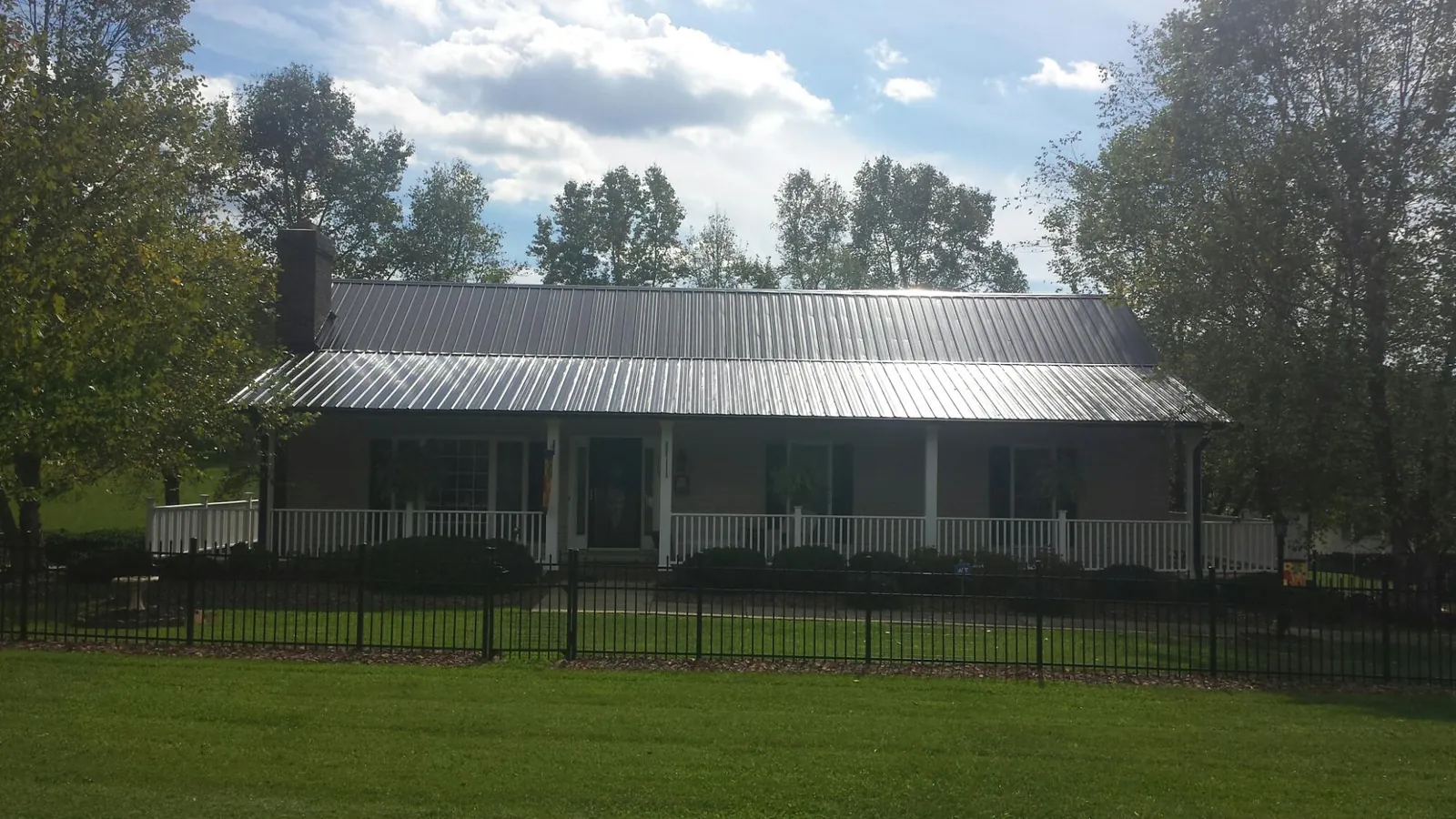 Gray metal roof on a brick ranch with a full width front porch — Gutter Guard Installation work by our crew in Matheson