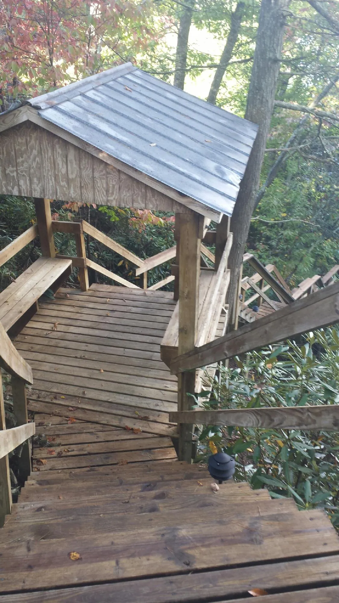 Metal roofed shelter over wooden steps on a wooded walkway — Skylight Repair & Installation work by our crew in Matheson