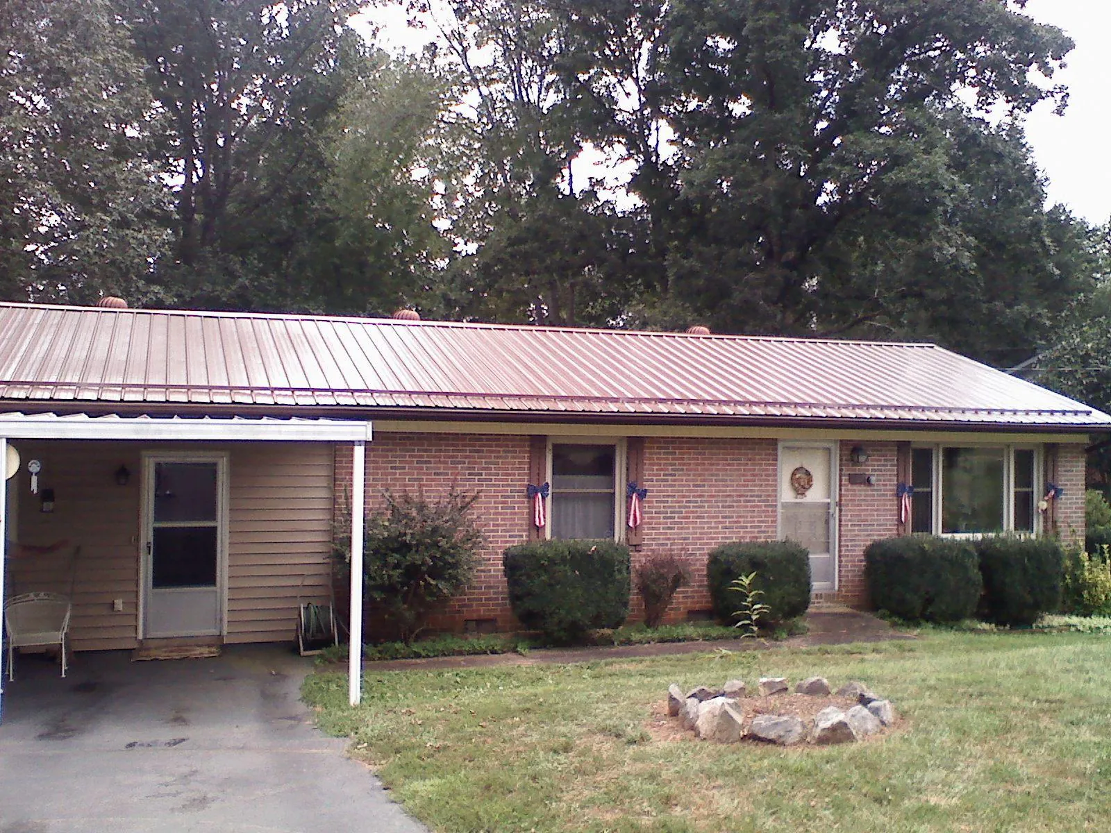 Bronze metal roof and carport on a brick ranch home — Roof Repair work by our crew in Matheson