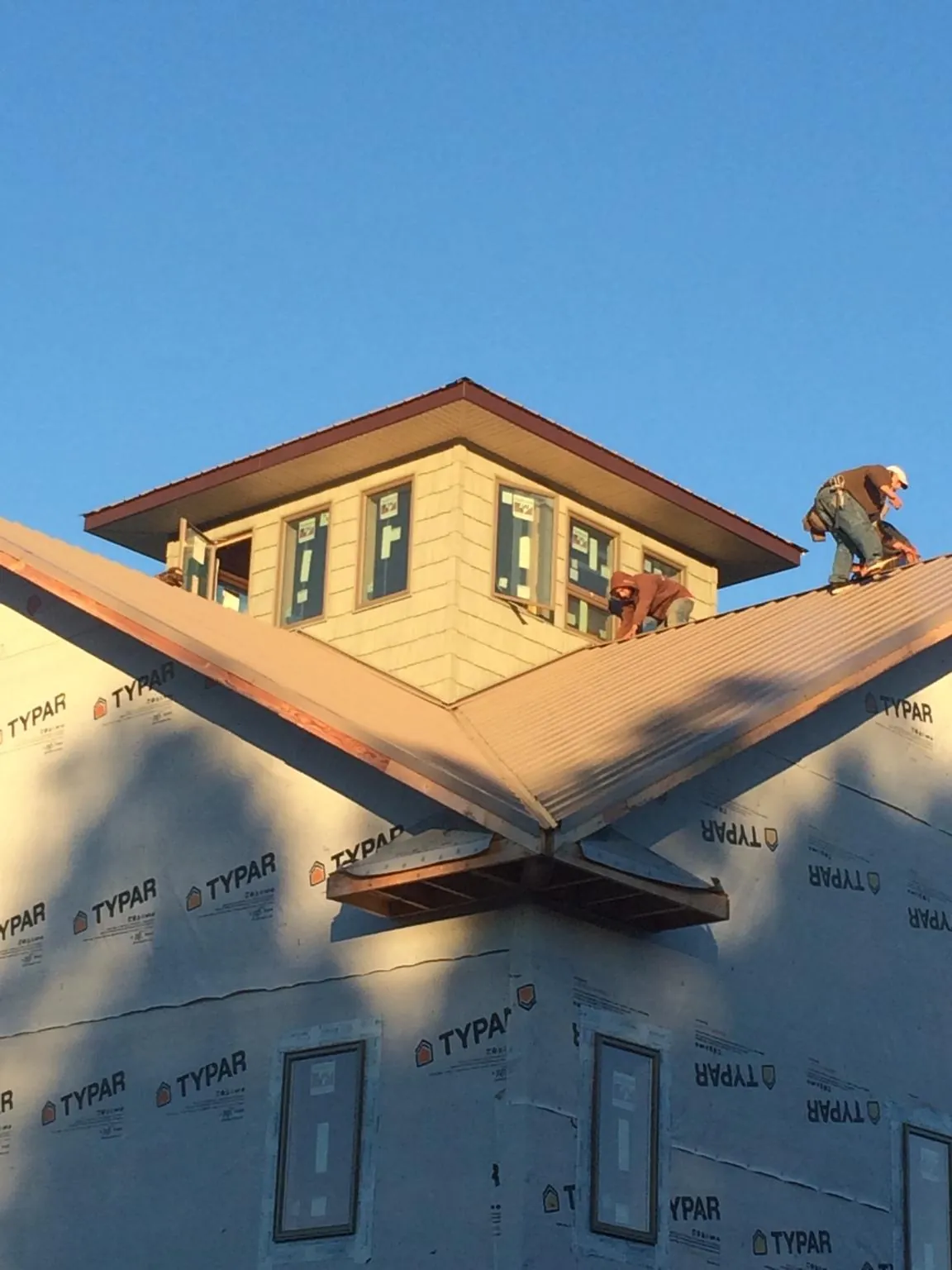 Roofers working around a rooftop cupola on a new metal roof at sunset — Roof Waterproofing in Matheson by Roofing Brothers